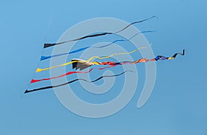 Parafoil kite with long colorful tail beside five streamer flags