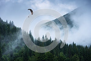 Paraglide silhouette above the cloudy carpathian forest