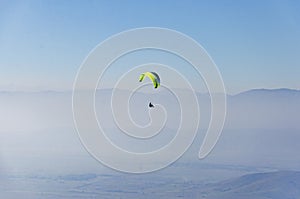 Paraglide silhouette above the misty valley