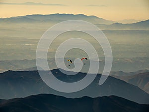 Paraglide silhouette flying over misty mountain