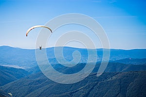 Paraglide silhouette flying over mountain peaks, beautiful rays of light in high mountain valley