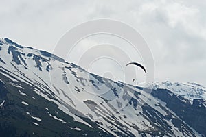 A paraglider in Alpine region with snowy slopes on the background. Scene from Engelberg region in Obwalden canton, Switzerland.