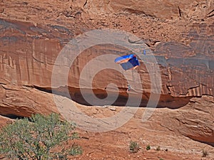 Paraglider drops to the ground along a canyon in Arches National Park.