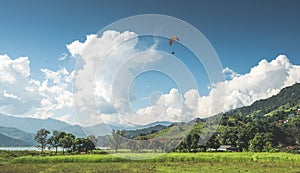 Paraglider flies over a meadow, Pokhara, Nepal