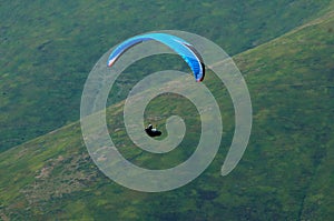 Paraglider flies over a mountain valley on a sunny summer day. Paragliding in the Carpathians in the summer.