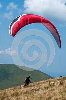 Paraglider flies over a mountain valley on a sunny summer day. Paragliding in the Carpathians in the summer.