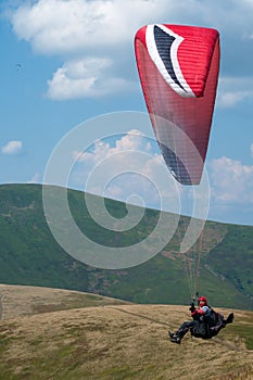 Paraglider flies over a mountain valley on a sunny summer day. Paragliding in the Carpathians in the summer.