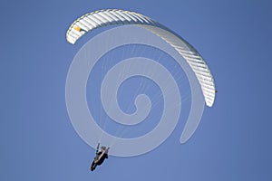 A paraglider flies in the sky under a multi-colored paraglider.Man