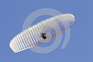 A paraglider flies in the sky under a multi-colored paraglider.Man