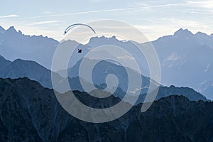 Paraglider flying above blue Mountains Silhouette, Allgaeu, Oberstdorf, Alps, Germany. Travel destination. Freedom and