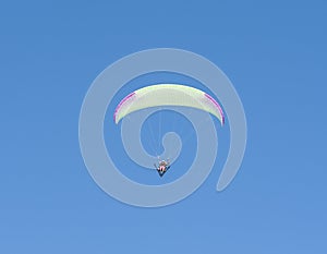 Paraglider flying against blue sky background