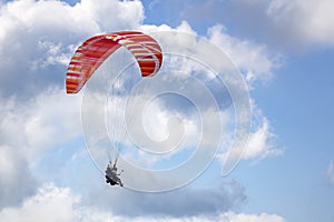 Paraglider flying against blue sky with clouds