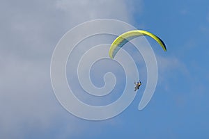 Paraglider is flying in the blue sky against the background of white clouds