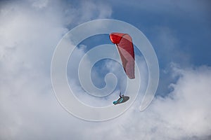 Paraglider is flying in the blue sky against the background of white clouds