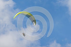 Paraglider is flying in the blue sky against the background of white clouds