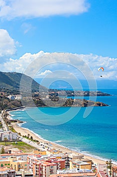 Paraglider flying over the amazing sea landscape by coastal Cefalu in Italian Sicily. Captured on a vertical photography