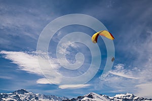 Paraglider flying over mountains at sunny summer day, Swiss Alps