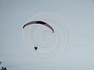 Paraglider flying on the parachute during sunset on the meadow.