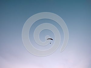 Paraglider flying on the parachute during sunset on the meadow.