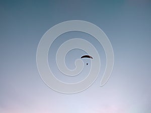 Paraglider flying on the parachute during sunset on the meadow.