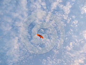 Paraglider flying on the parachute during sunset on the meadow.