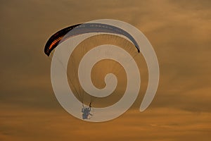 Paraglider flying with paramotor on sunset