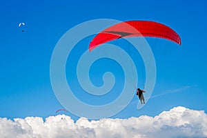 The paraglider hovers in the sky high above the clouds