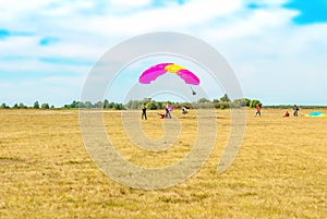 Paraglider landing on summer field by blue sky