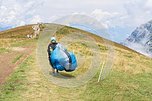 Paraglider pilot with his paraglider on his way to the top of Monte Baldo on Lake Garda