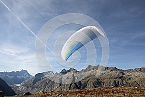 Paraglider Pilot stands on a slope and balances his paraglider above his head in the Alps of Switzerland photo