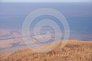 Paraglider silhouette flying on blue sky background. Nature landscape.