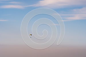 Paraglider silhouette flying on blue sky background. Nature landscape.