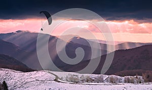 Paraglider silhouette over the rays of sunset light