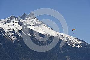 Paraglider soaring in front of snow-capped peaks of the Valais Alps