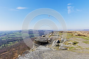 Paraglider soaring over Curbar Edge on a spring morning