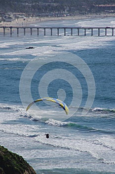 Paraglider, surfers, swimmers near Scripps Pier, La Jolla, California