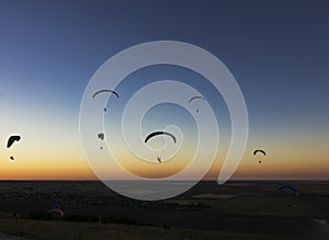 Paragliders in the evenyng sky with low light