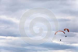 Paragliders flying, against a cloudy sky