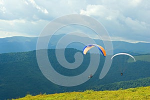 Paragliders flying low over top of Carpathian green mountains