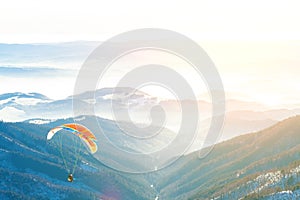 Paragliders launched into air from the very top of a snowy slope during golden hour