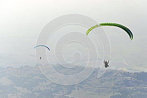 Paragliders silhouette flying over misty mountain