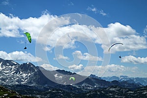 The paraglides are flying above the mountains