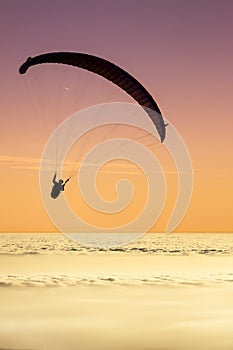 Paragliding above a sea of clouds with a pastel sky