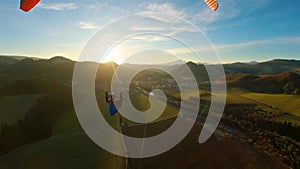 Paragliding flight above green spring countryside nature at golden sunset flying freedom adrenaline adventure