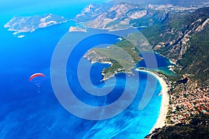 Paragliding flight over the blue lagoon of the Mediterranean Sea. Red dome of the parachute against the blue sea. Turkey. Oludeniz