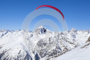 Paragliding in the mountains, People paragliding tandem above mountain in winter in Dombay ski resort. Concept of active lifestyle