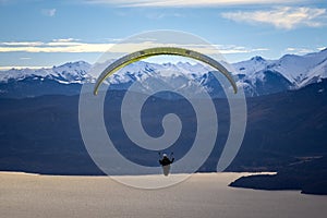 Paragliding over Nahuel Huapi lake and mountains of Bariloche in Argentina, with snowed peaks in the background. Concept of
