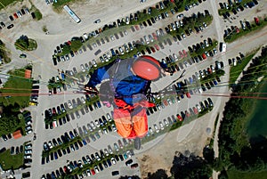 paragliding pilot flying high over parking lot of Brauneck cable car