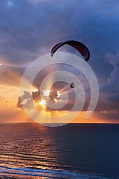 Paragliding at sunset on sea with sun beams