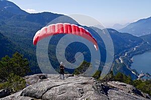 Paragliding. Woman with a red paraglider on the top of the mountain.